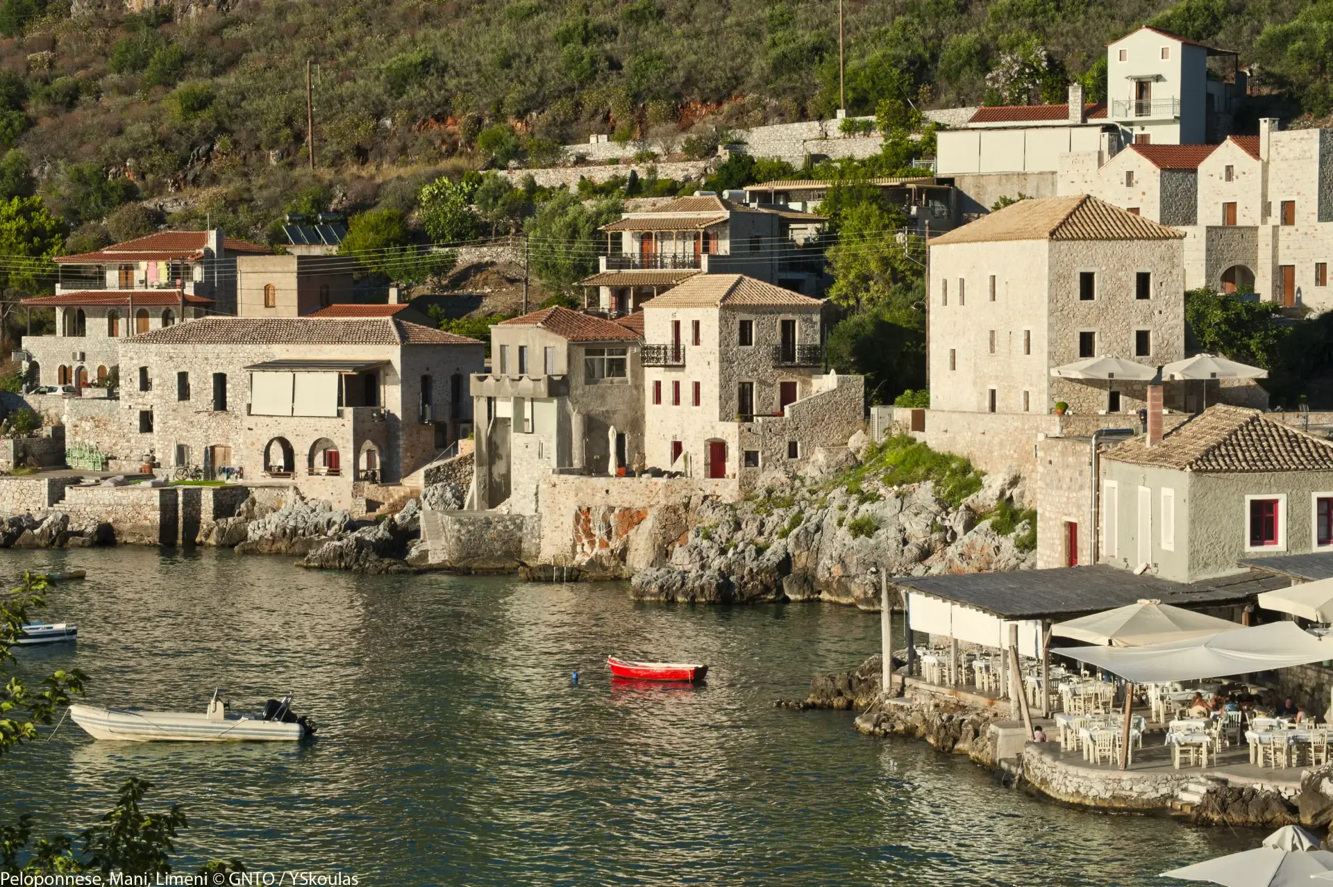 Traditional Mani stone tower houses overlooking dramatic coastline with mountain backdrop